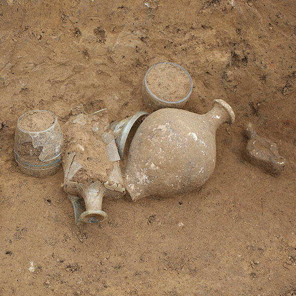 Freigelegte Nische eines Brandgrabes mit Öllämpchen, Krug und Glasgefäßen
